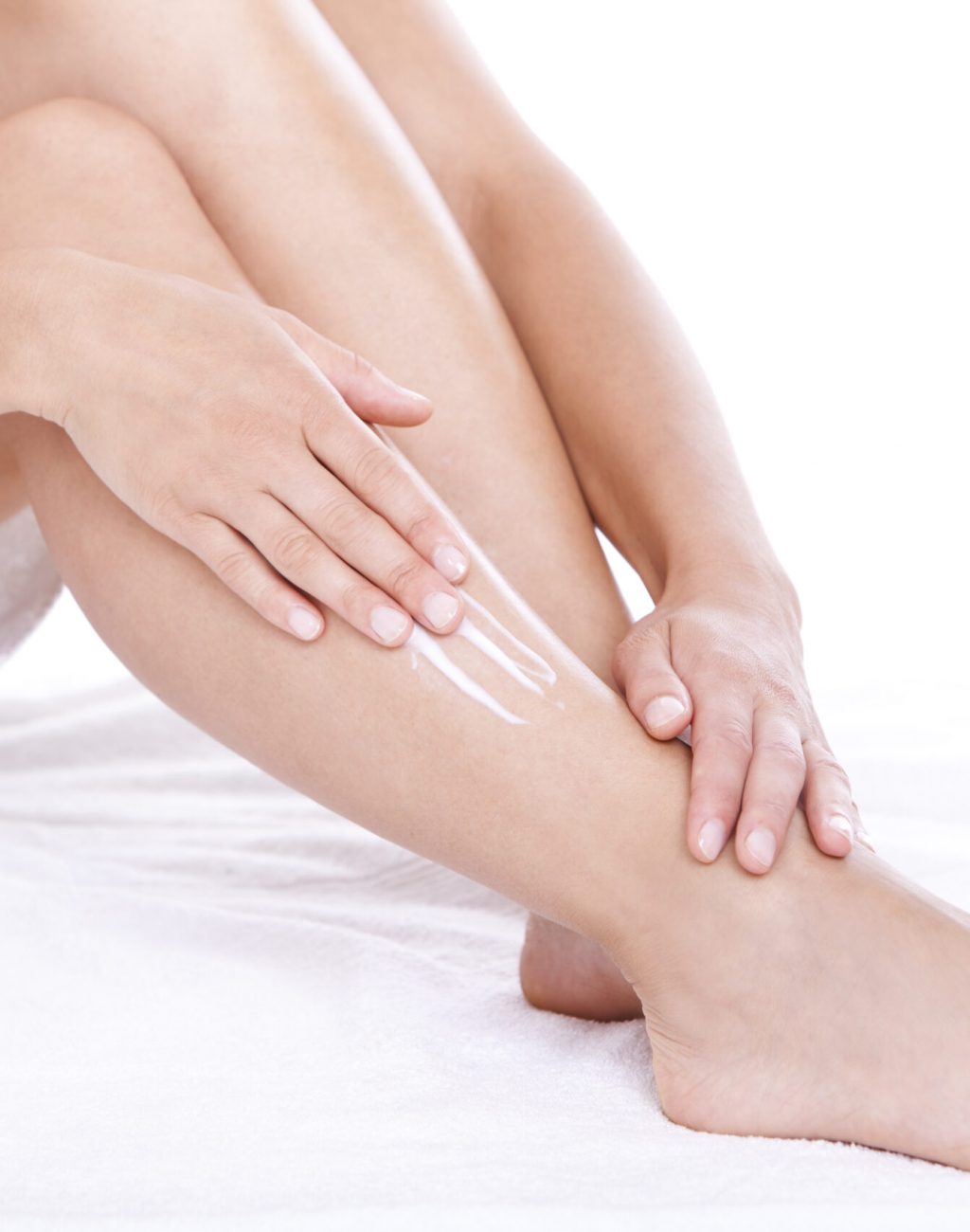 Woman applying moisturizer cream on the legs  over white background